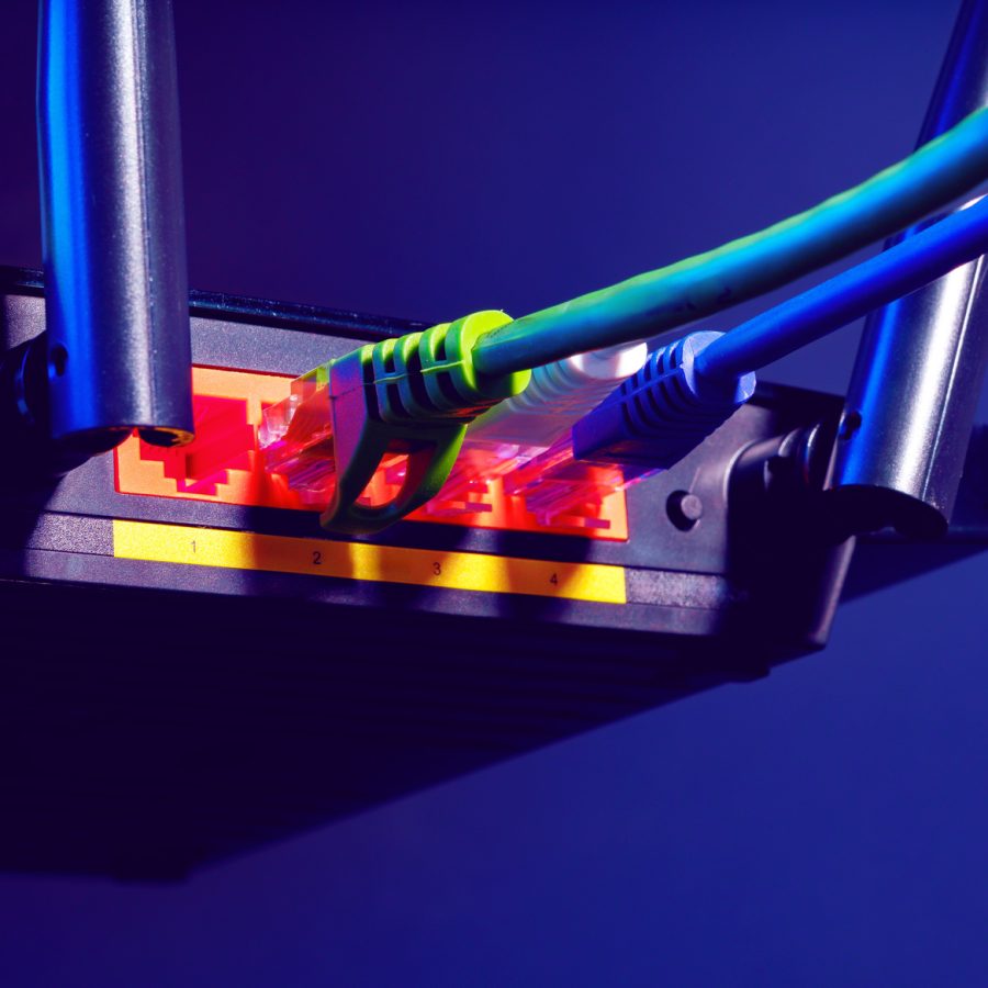 Cables plugged in a Wi-Fi router on dark background close up